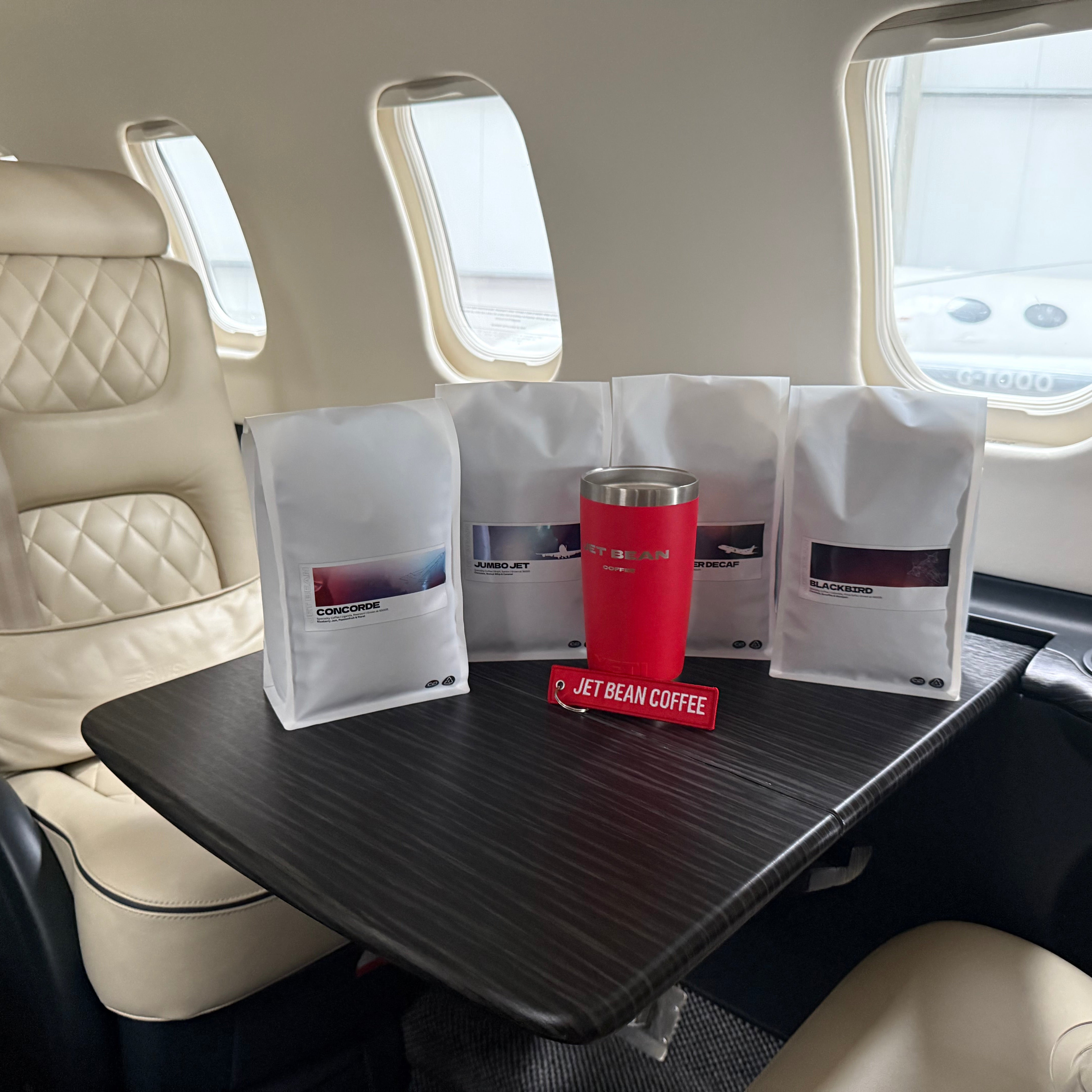 Airplane seat with a tray table featuring a red cup and coffee packages.