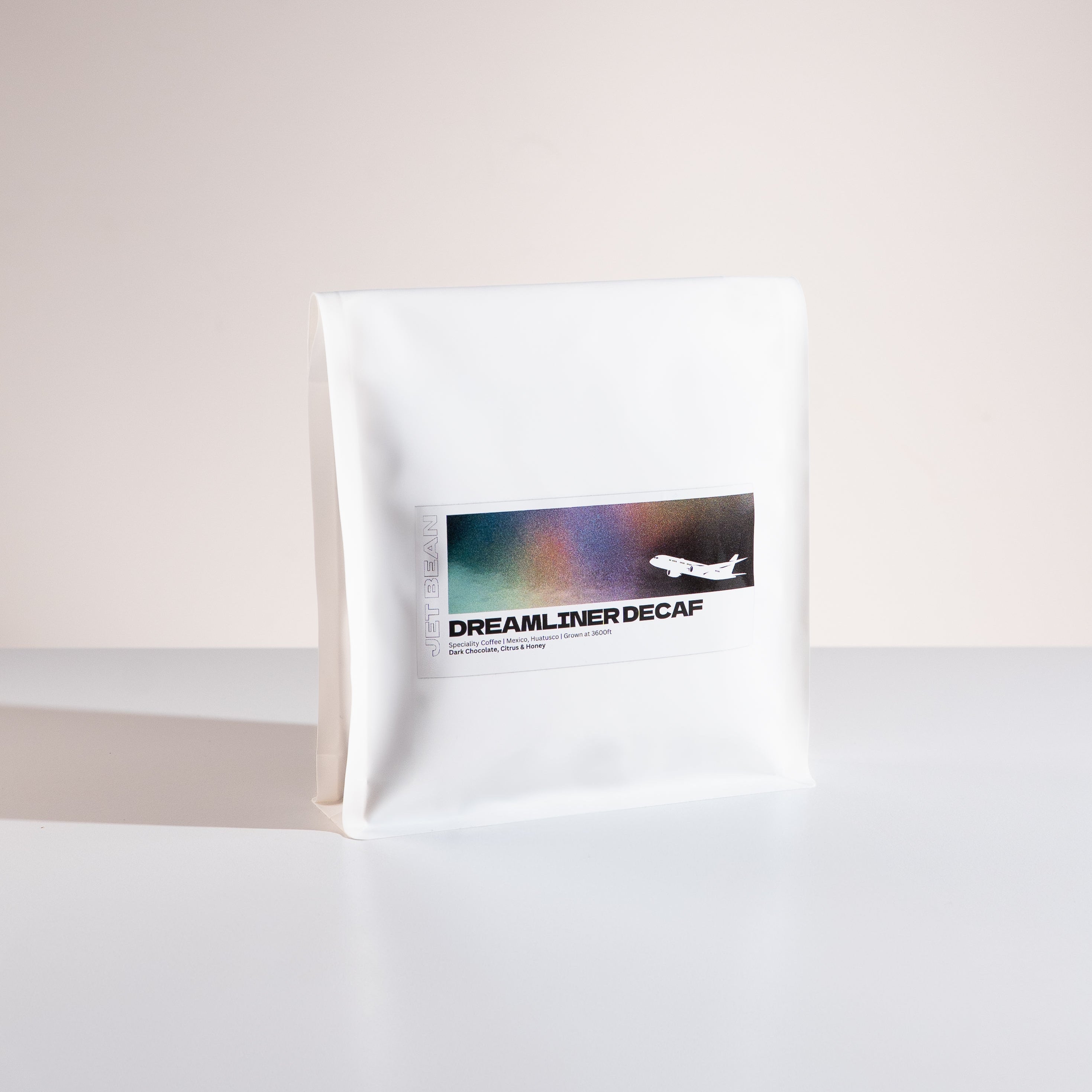 White coffee bag labeled 'Dreamliner Decaf' on a light gray background